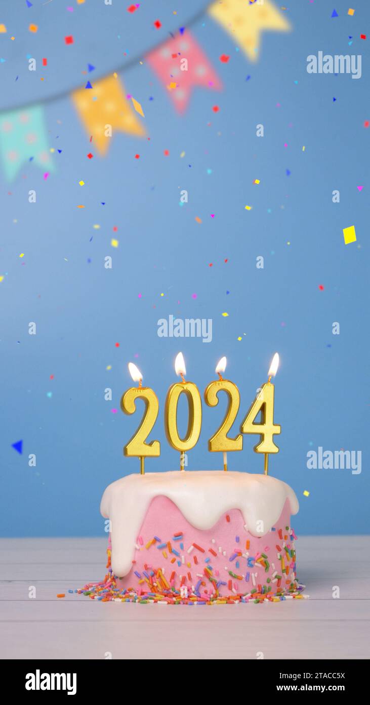 Happy New Year 2024, süßer Kuchen mit goldener Kerze Nummer 2024 für die Neujahrsfeier wurde mit bunten Konfetti und Fahnenfahne angezündet Stockfoto
