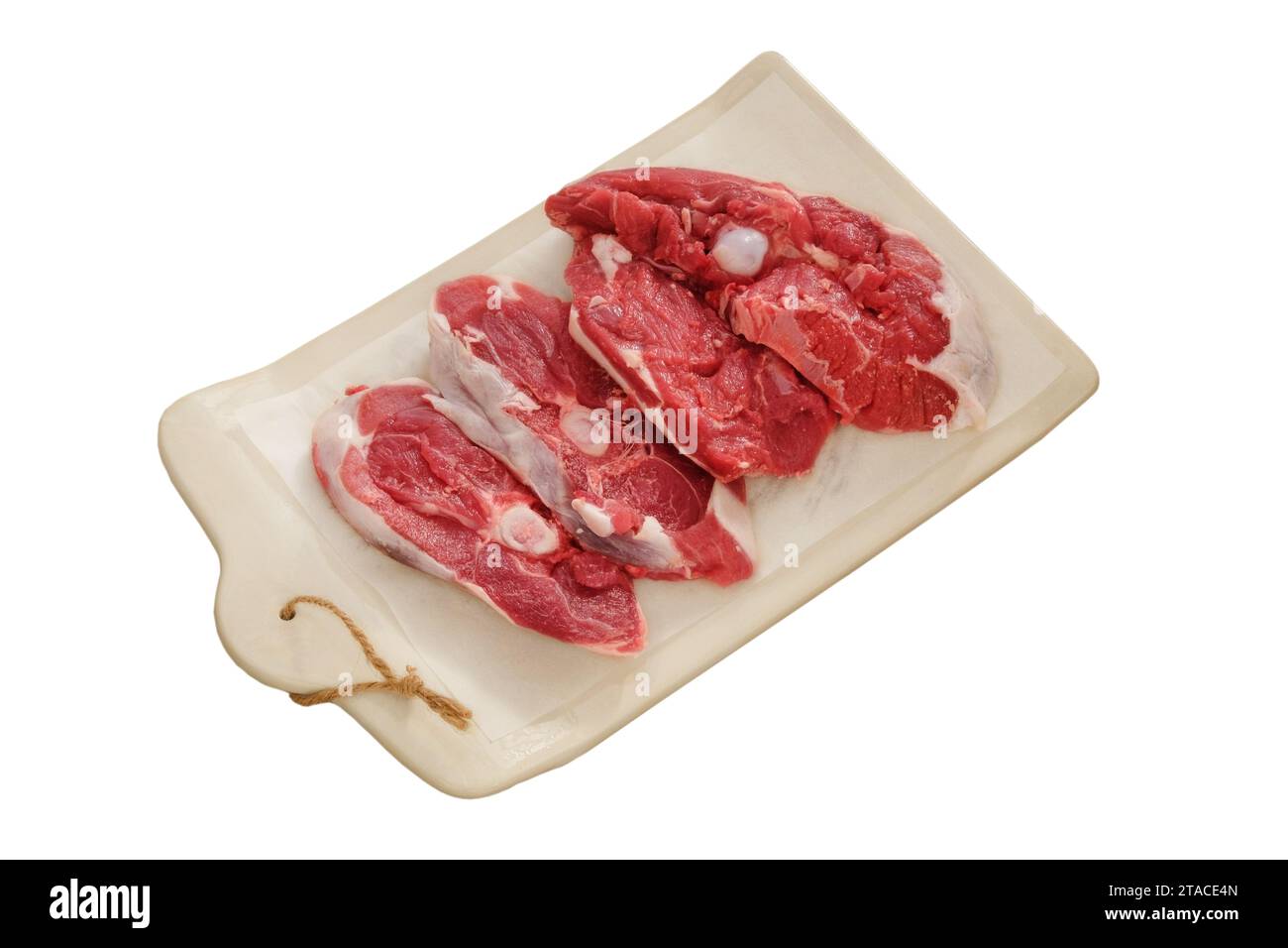 Lammfleisch auf einem Keramikbrett isoliert auf weißem Hintergrund. Fleischstücke zum Kochen. Hinterer Teil des Schlachtkörpers. Stockfoto
