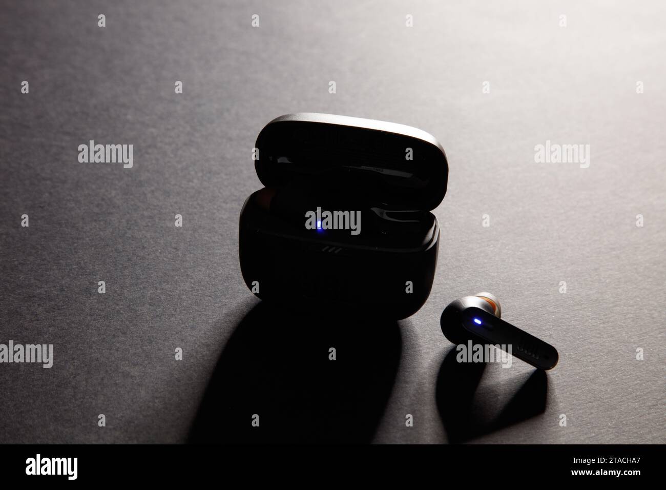 Eine Studioaufnahme eines schwarzen jbl Wireless bluetooth-Ohrhörers vor einem dramatisch beleuchteten schwarzen Hintergrund Stockfoto