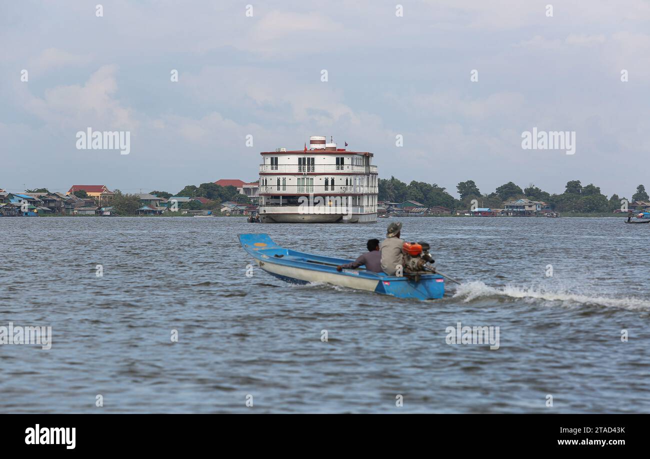 Lokales Khmer-Motorboot, das in der Nähe des luxuriösen Kreuzfahrtschiffs Jahan (Heritage Line), Mekong-Flussrundfahrten, Kambodscha (Tonle SAP Lake) und Vietnam (Saigon) vorbeifährt Stockfoto
