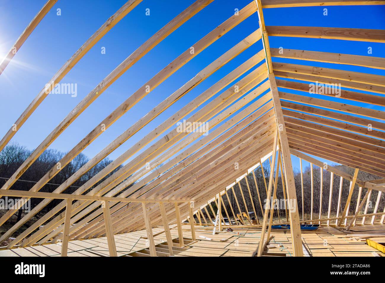 Das Dach des neuen Hauses wird mit Traversen gebaut, die von Holzbalken gestützt werden Stockfoto