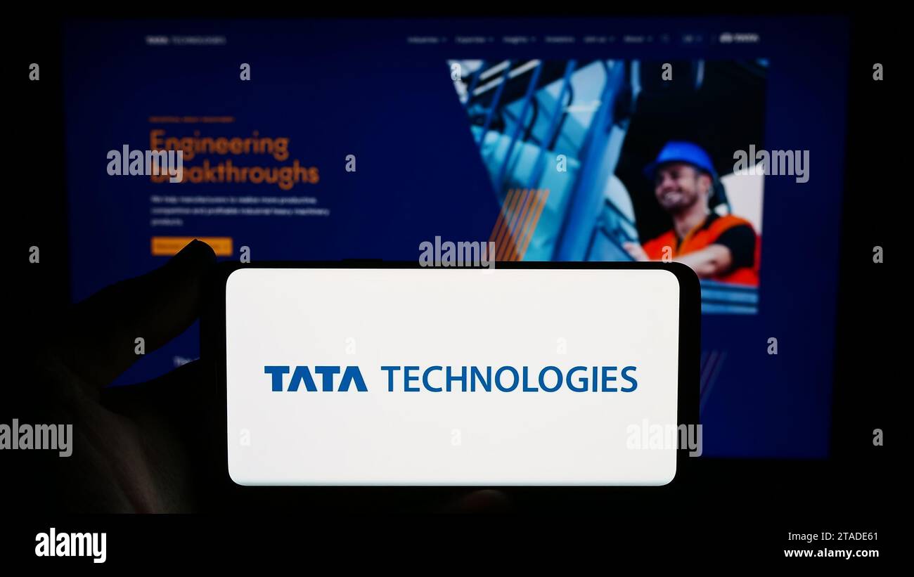 Person mit Smartphone und Logo des indischen Ingenieurunternehmens Tata Technologies Limited vor der Website. Schwerpunkt auf dem Display des Telefons. Stockfoto