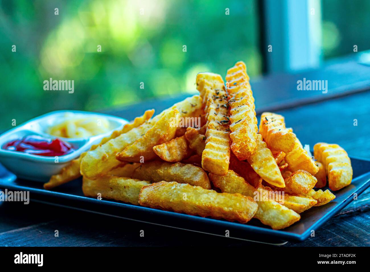 Knusprige Pommes Frites mit Crinkle-Cut: Unwiderstehliche Kartoffeln mit köstlicher Sauce Stockfoto