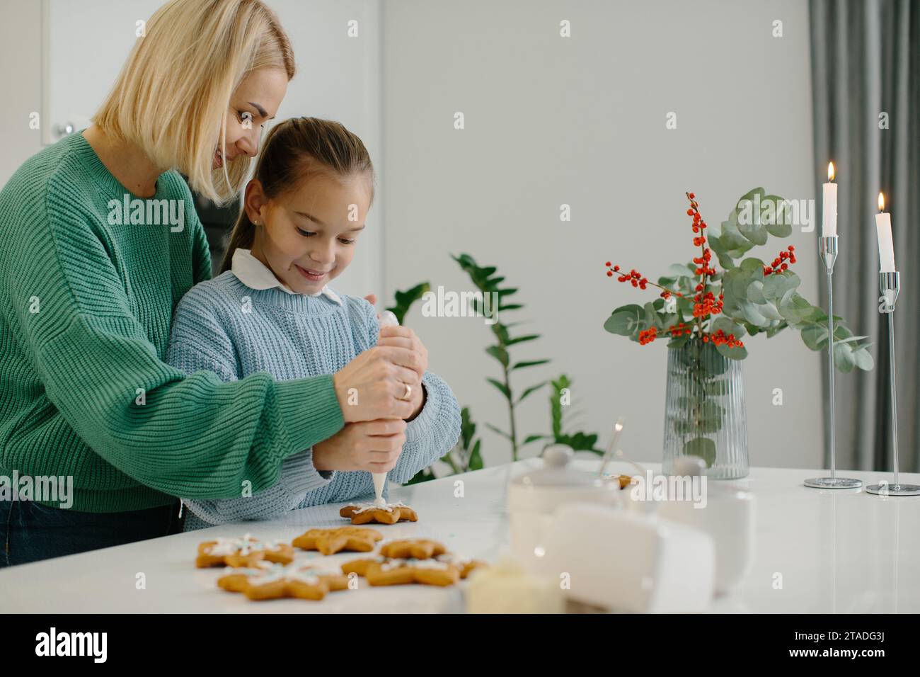 Mutter und Tochter bereiten Weihnachtskekse zu und dekorieren sie mit