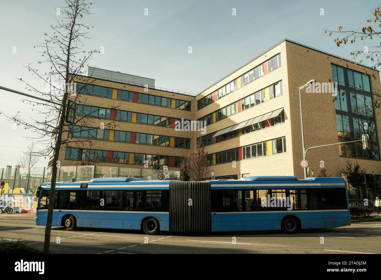 Öffentlicher Nahverkehr, Gelenkbus vor der kommunalen Berufsschule für Kinderbetreuung in München-Sendling Stockfoto