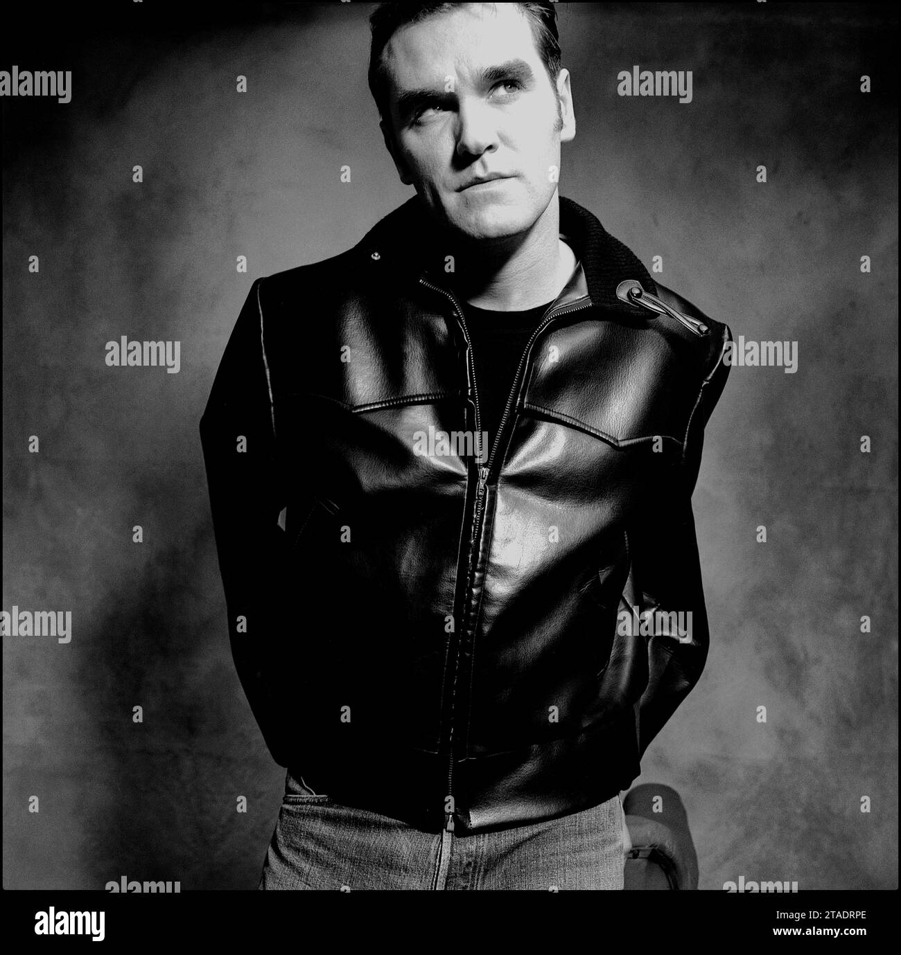 Das leistungsstarke Schwarzweiß-Porträt des legendären Rockstars, Sängers/Songwriters Morrissey in Lederjacke und blauer Jeans, um 1995 für Parlophone Records seine Single Sunny zu bewerben. Stockfoto