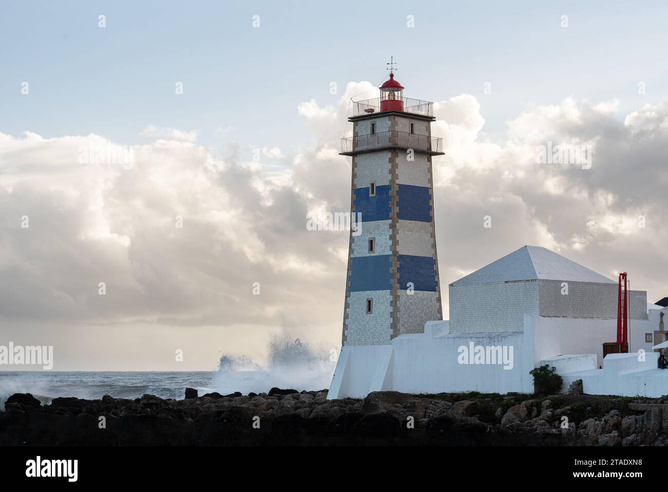 Große Wellen stürzen in das Fundament des Leuchtturms Santa Marta im Hafen von Cascais in Portugal Stockfoto