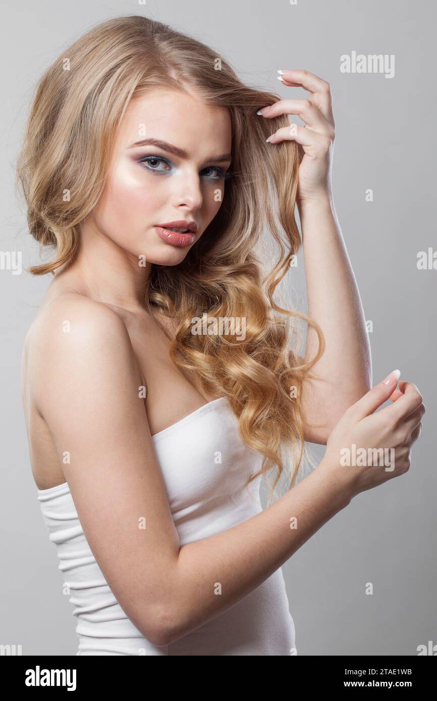 Fröhliche Dame mit lockiger Frisur, die auf weißem Hintergrund steht. Beauty Woman Porträt Stockfoto