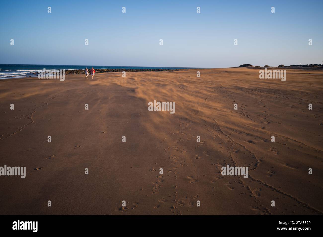 Ein paar Spaziergänge am Strand, während ein starker Wind Sand auf Lanzarote, Kanarischen Inseln, Spanien weht Stockfoto