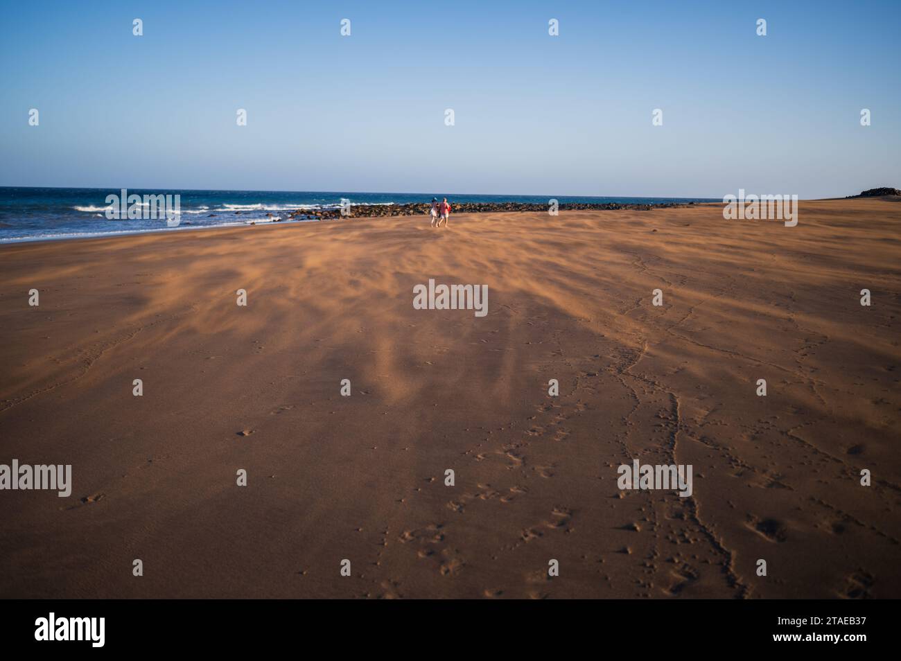 Ein paar Spaziergänge am Strand, während ein starker Wind Sand auf Lanzarote, Kanarischen Inseln, Spanien weht Stockfoto