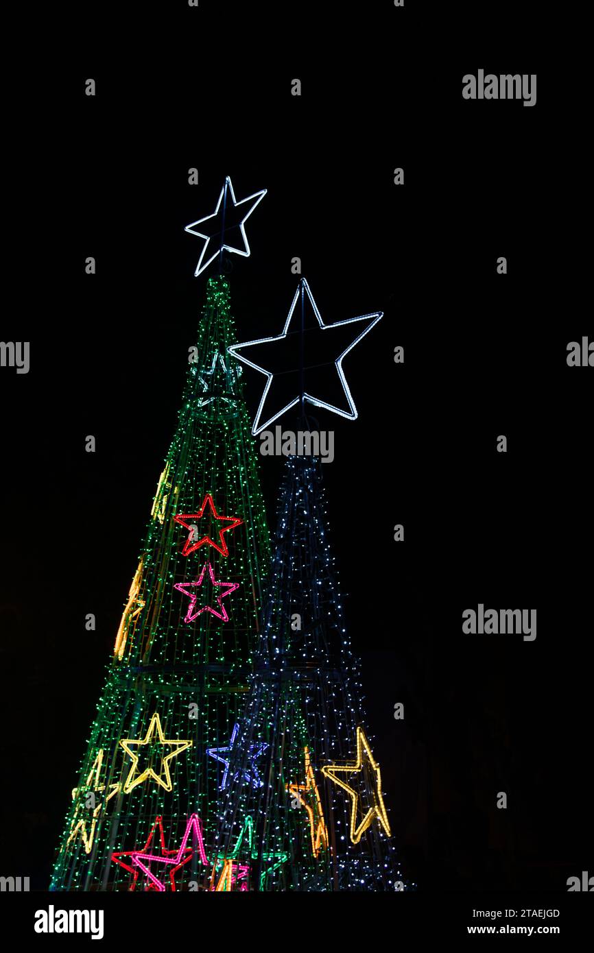 Bild auf Schwarz von zwei Weihnachtsbäumen, die mit LED-Leuchten gebaut wurden, um die Stadt im gesunden Wettbewerb zu schmücken Stockfoto