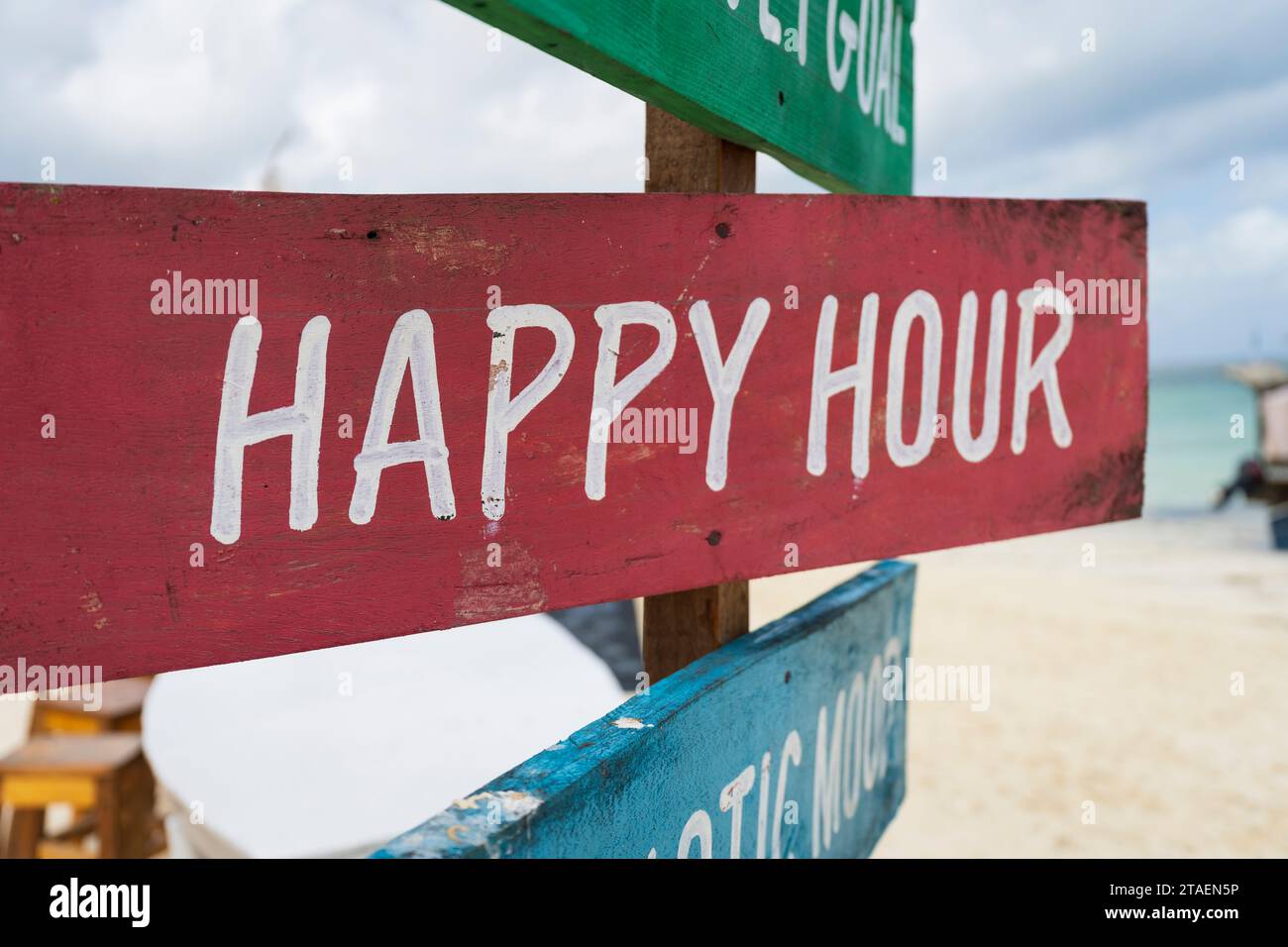 Farbenfrohes Schild mit der Aufschrift „Happy Hour“ am Sandstrand an sonnigem Tag, Relax und Sommerkonzept. Stockfoto