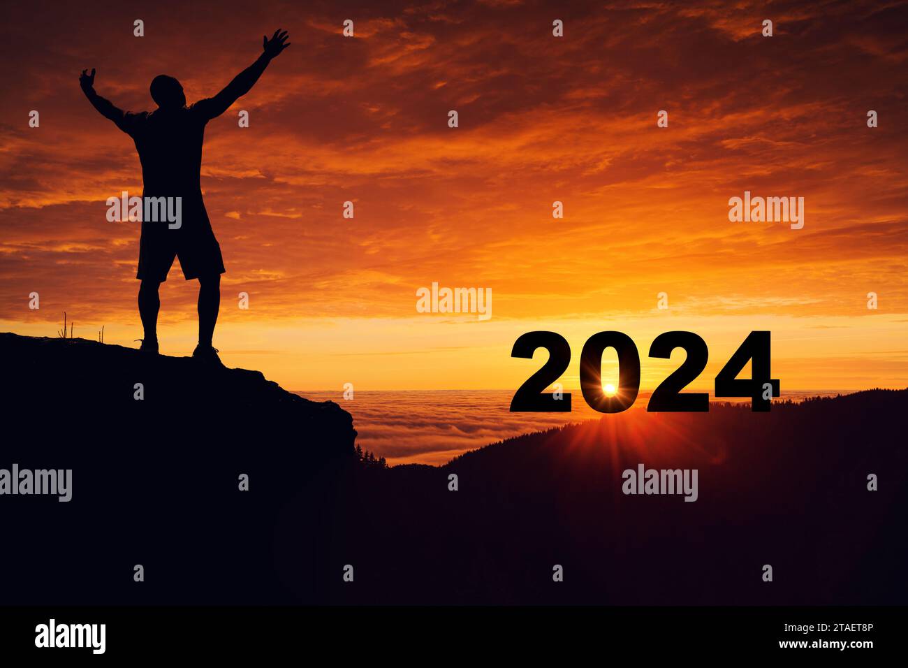 Mann Silhouette auf dem Berggipfel, der den Sonnenaufgang und 2024 Jahre beim Feiern beobachtet. Stockfoto