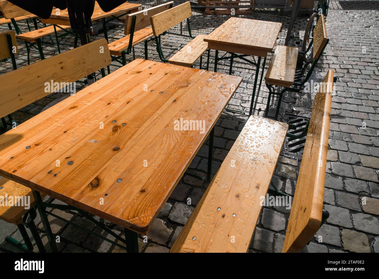 Holztische und -Stühle draußen im Garten unter dem Regen. Stockfoto