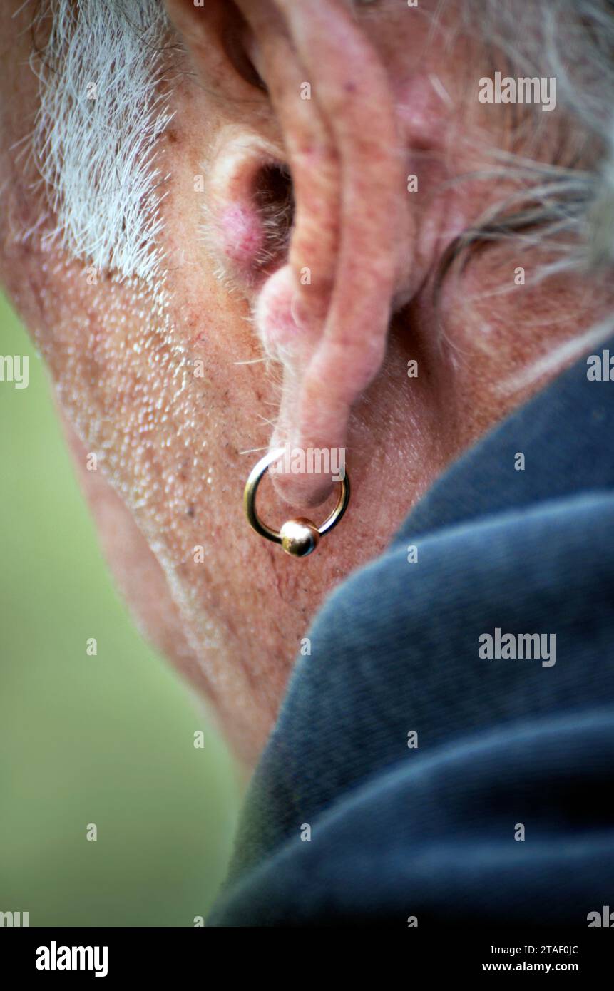 Alter unrasierter Mann mit goldenem Ohrring Stockfoto