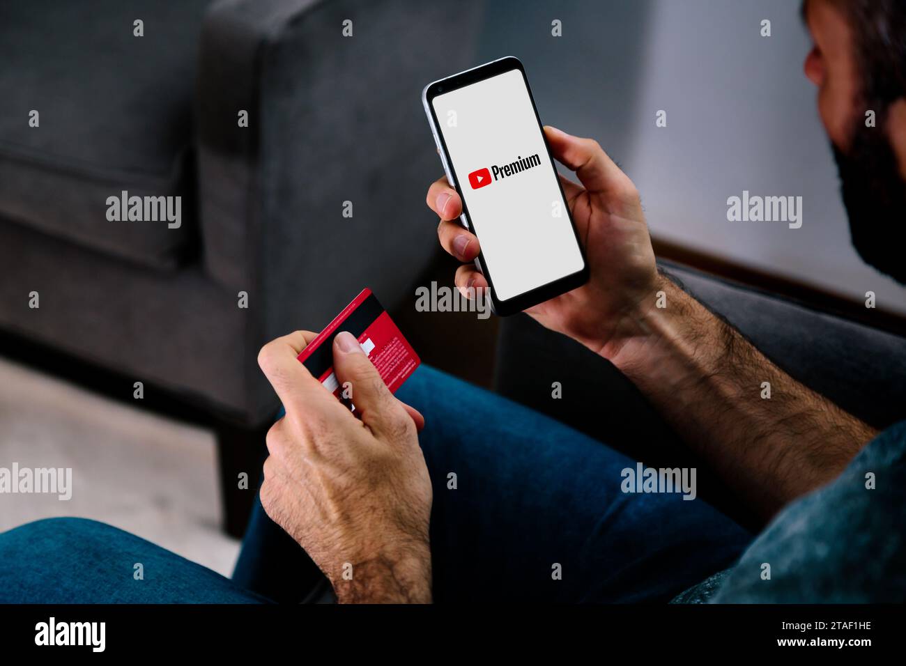 YouTube Premium-App auf dem Smartphone-Bildschirm. Mann, der mit Kreditkarte für Prämienantrag bezahlt. Stockfoto