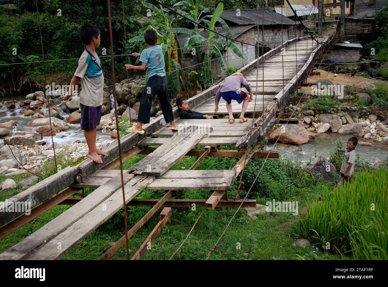 Kinder spielen auf einer hölzernen Hängebrücke in einem Dorf. Kinder im Freien aktiv Stockfoto