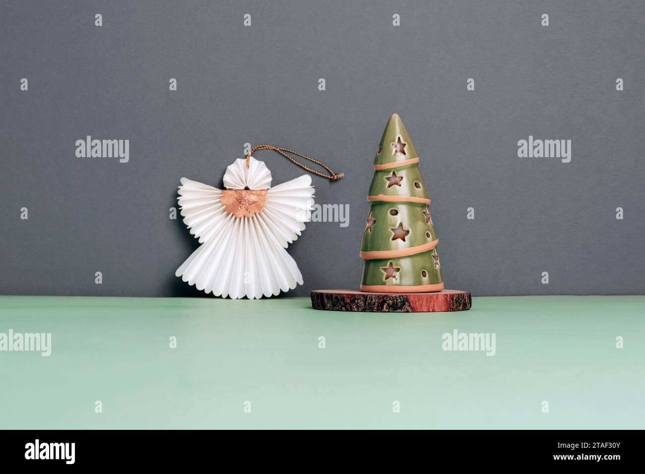 Dekorativer Weihnachtsbaum und Papierengel auf einem grünen Tisch vor einer grauen Wand. Weihnachtskonzept. Selektiver Fokus. Stockfoto