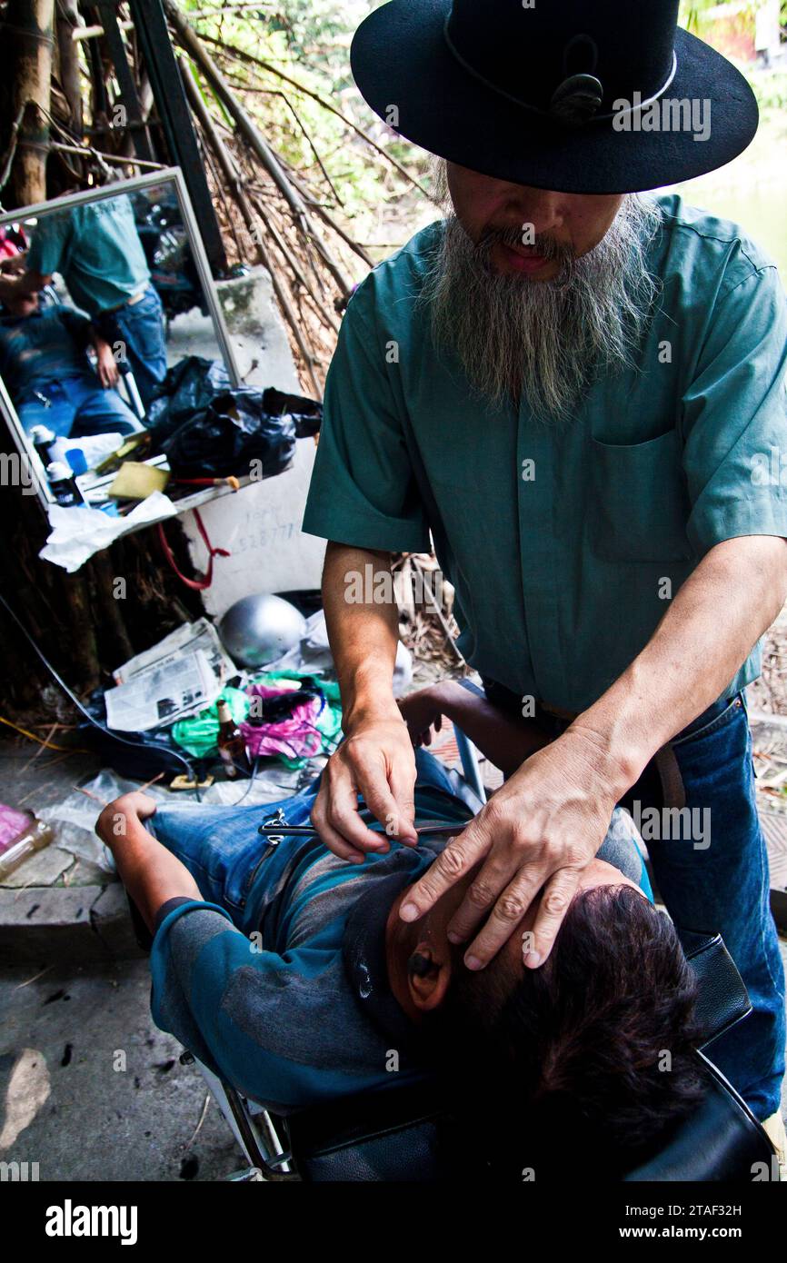 Ein Straßenfriseur schneidet einem Kunden in Hanoi, Vietnam, die Haare Stockfoto