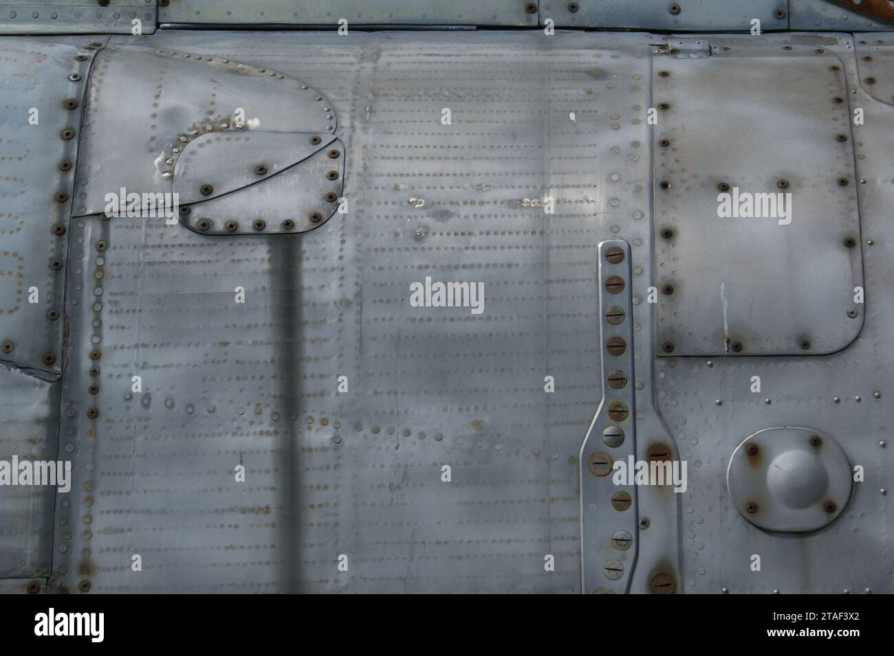 Metallischer Hintergrund mit Schrauben und Nieten. Ein Fragment des Rumpfes. Stockfoto
