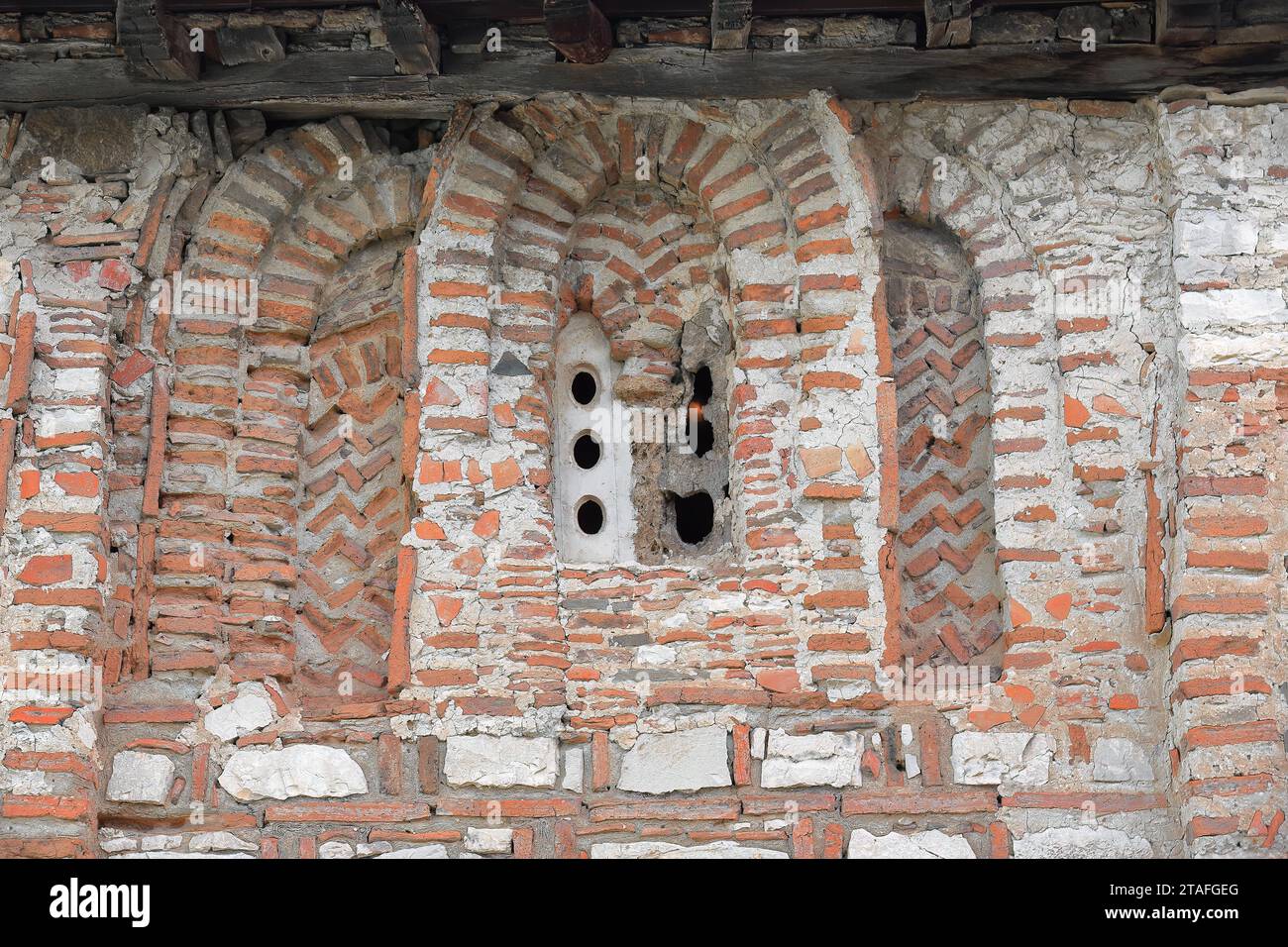 085 Rundbogen, Pfostenfenster aus rotem Ziegelwerk, das in die südwestliche Wand der Kirche St. Maria Vllaherna geschnitten wurde. Berat-Albanien. Stockfoto