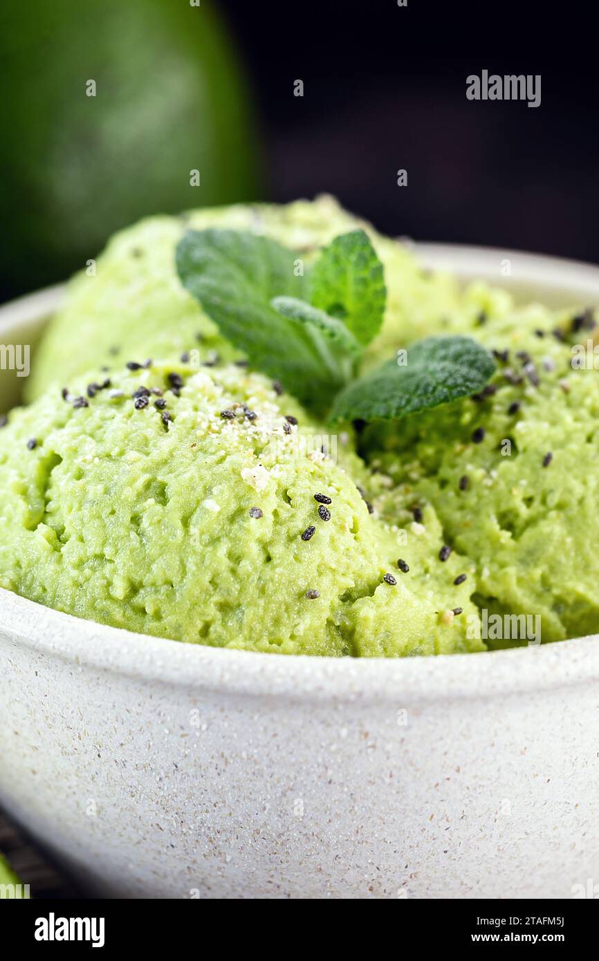 Hausgemachtes Avocado-Eis, hergestellt aus gefrorenen Bio-Früchten ohne Zusatz von Zucker oder Milchprodukten. Veganes Dessert. Dessert in biologisch abbaubarer Plastikschüssel serviert. Stockfoto