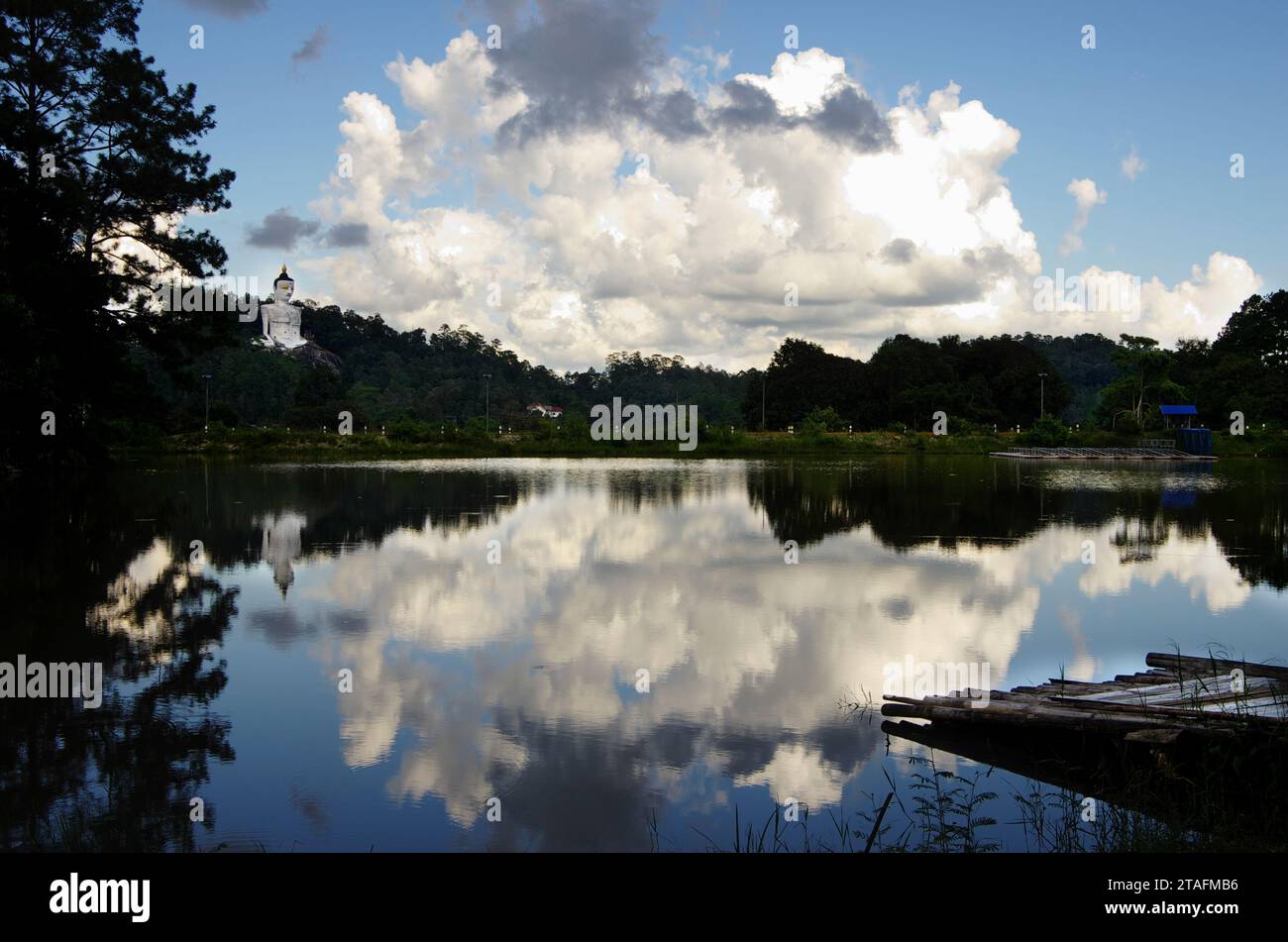 Reflexion der Wolken und des blauen Himmels auf dem See und der weißen Buddha-Statue am Ufer. Mae Sa Valley. Nord-Thailand. Stockfoto