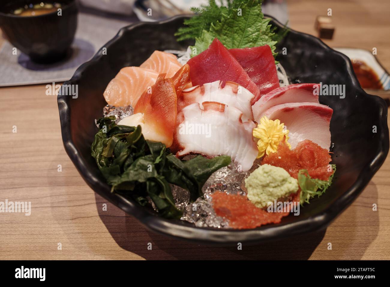 Blick von oben auf Sashimi mit verschiedenen rohen frischen Scheiben Fisch, Tintenfisch und Tintenfisch, auf der Holztheke. Stockfoto