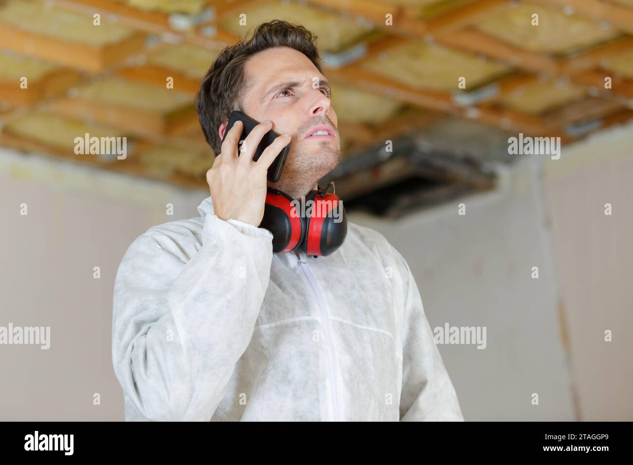Builder am Telefon von einer Leiter Stockfoto