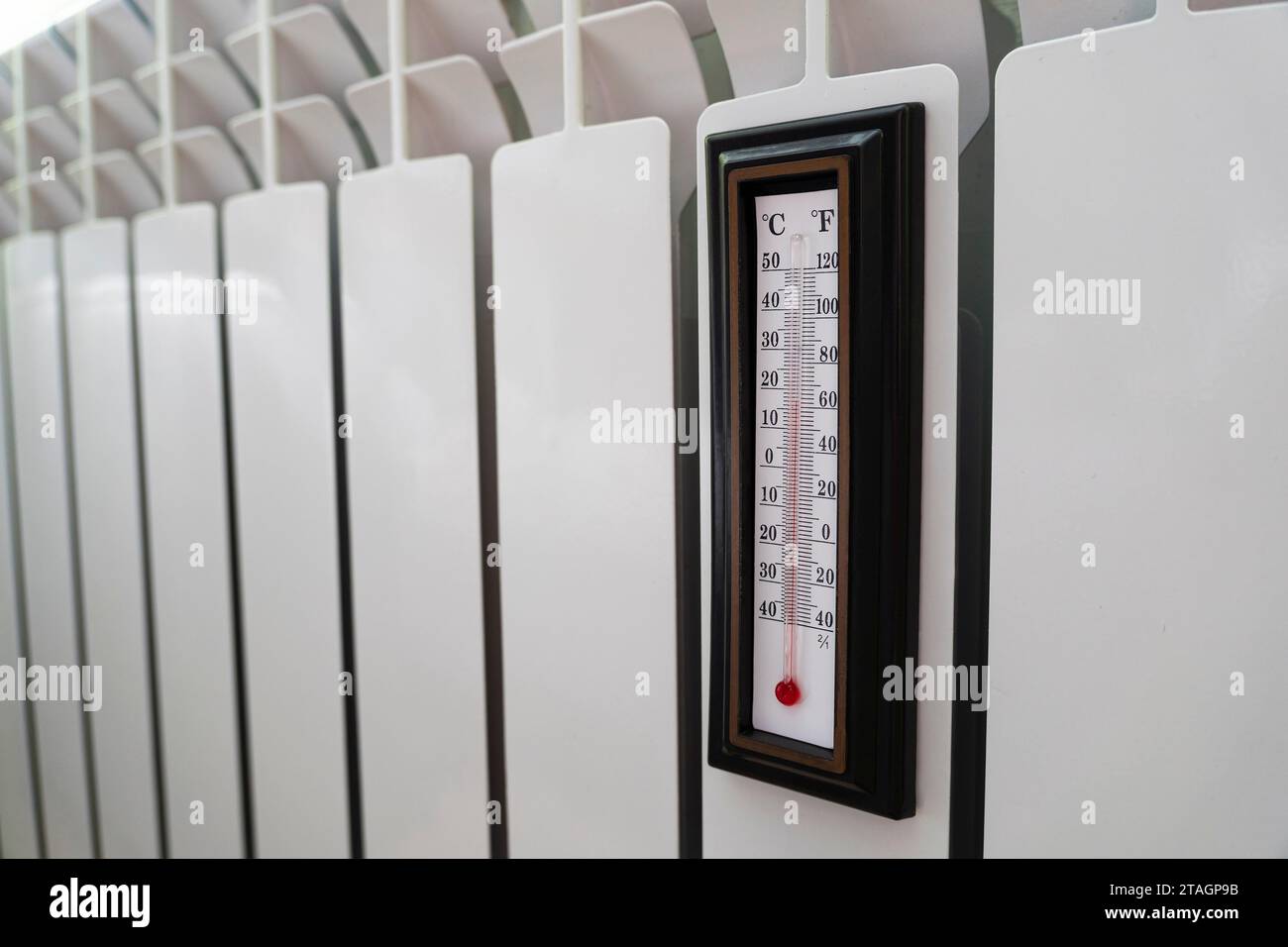 Heizkörper Thermostat auf niedrige Temperatur und Raumthermometer eingestellt, um Geld bei Heizkosten zu sparen. Energiekrise, Energieeffizienz und Anstieg Stockfoto