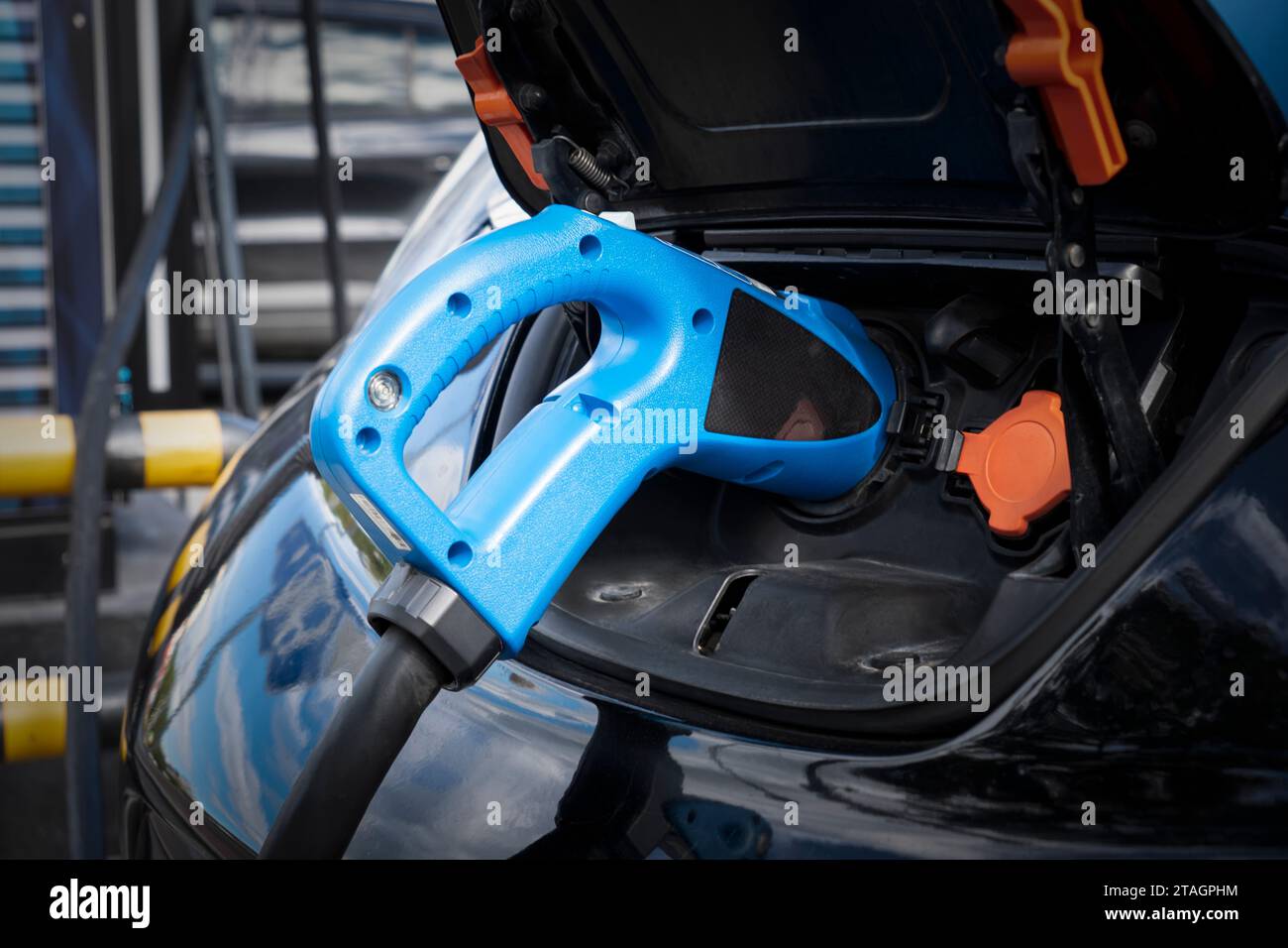 Elektroauto-Aufladung auf dem Parkplatz mit Elektroauto-Ladestation auf der Stadtstraße. Nahaufnahme des Netzteils, das blau an eine elektrische C angeschlossen ist Stockfoto