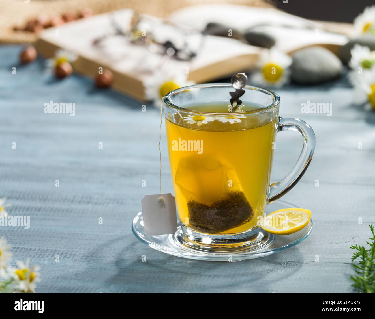 Kräutertee-Beutel in einer Glasschale. Kamillenteebeutel. Heißgetränk-Konzept am Schreibtisch Stockfoto
