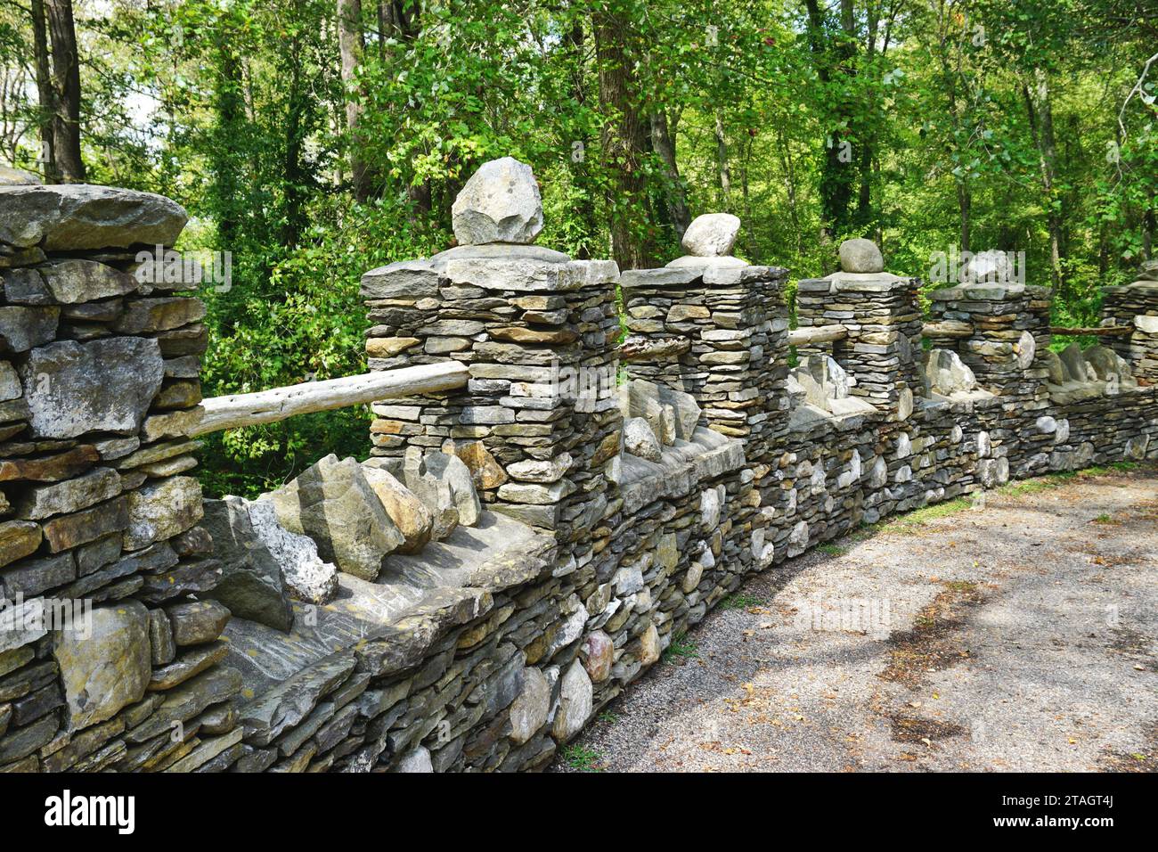 Eine alte Steinbarriere aus gestapelten trockenen Feldsteinen und Baumstämmen, die mit Mörtel gekrönt sind, säumt die Straße im Gillette Castle State Park in Connecticut. Stockfoto