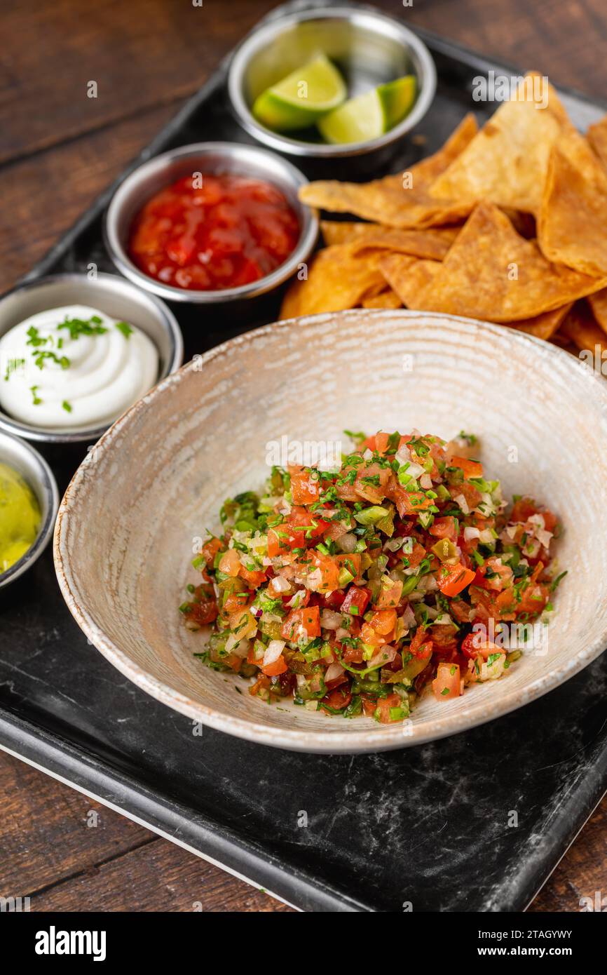 Pico de gallo aus mexikanischer Küche mit eintauchenden Saucen auf Holztisch Stockfoto