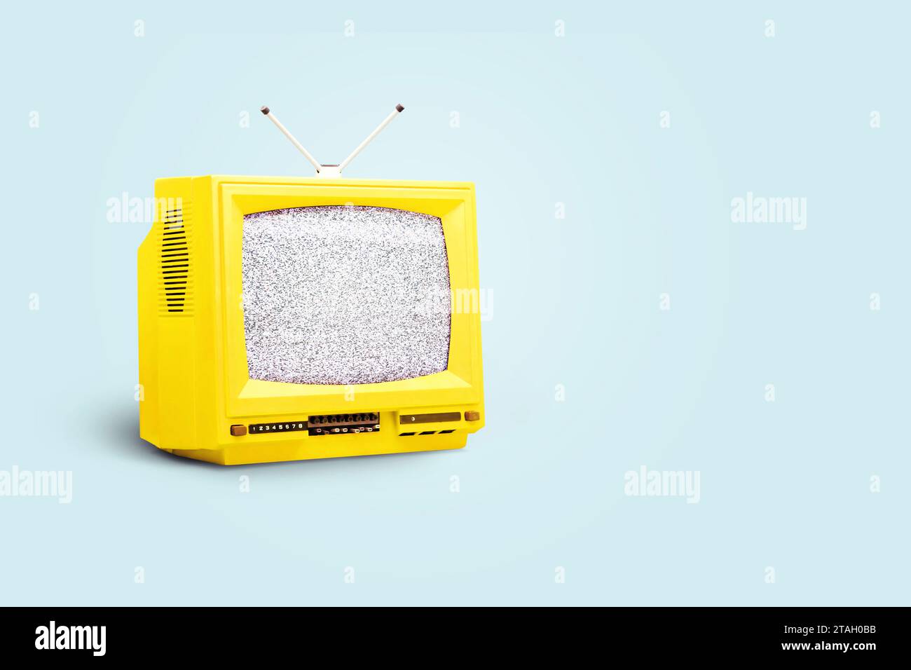 Gelber Vintage-Fernseher mit weißem Rauschen auf blauem Hintergrund. Kreative Idee, Propaganda und Medien Stockfoto