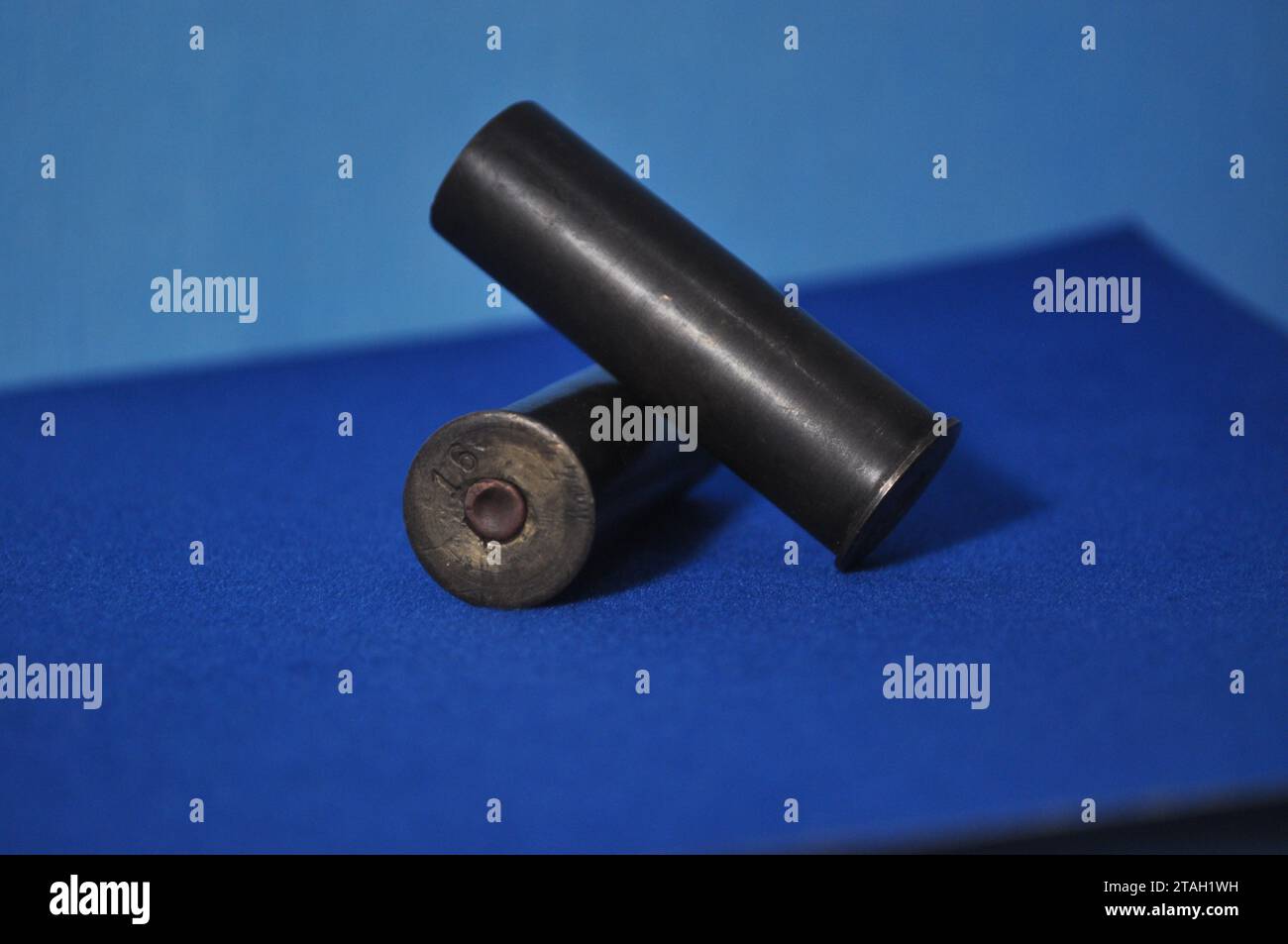 Eine schwarze Pistole mit dem Zylinder, der direkt auf die Kamera zeigt, auf einem hellblauen Hintergrund Stockfoto