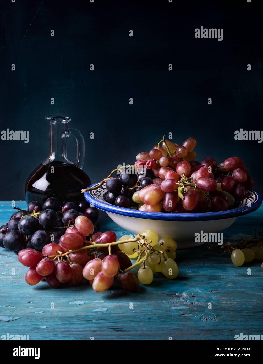 Flasche Rotwein mit Trauben auf einem alten hölzernen Hintergrund. Stockfoto