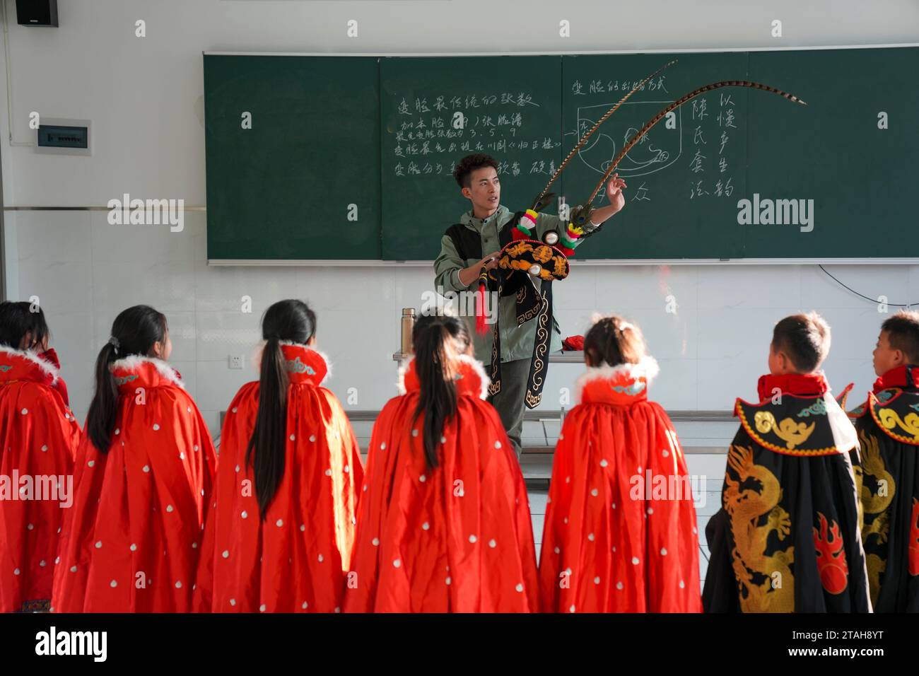 (231201) -- CHONGQING, 1. Dezember 2023 (Xinhua) -- der Volkskünstler Li Yong erklärt die Dekorationen, die in der traditionellen „bian lian“-Performance verwendet wurden, oder die Gesichtsveränderung, an der Wu'an Grundschule im Bezirk Dianjiang im Südwesten Chinas in Chongqing, 28. November 2023. Mit mehr als 600 Schülern kooperierte die Wu'an Grundschule in den letzten Jahren mit dem Volkskünstler Li Yong und fügte Gesichtswechsel als besonderen Teil ihres Lehrplans hinzu. Die Technik des Gesichtswechsels ist einer der berühmtesten Teile der Sichuan Opera, bei der Schauspieler schnell ihr Gesicht in atemberaubender und dramatischer Wirkung verändern. (Xinhua/Liu Chan) Stockfoto