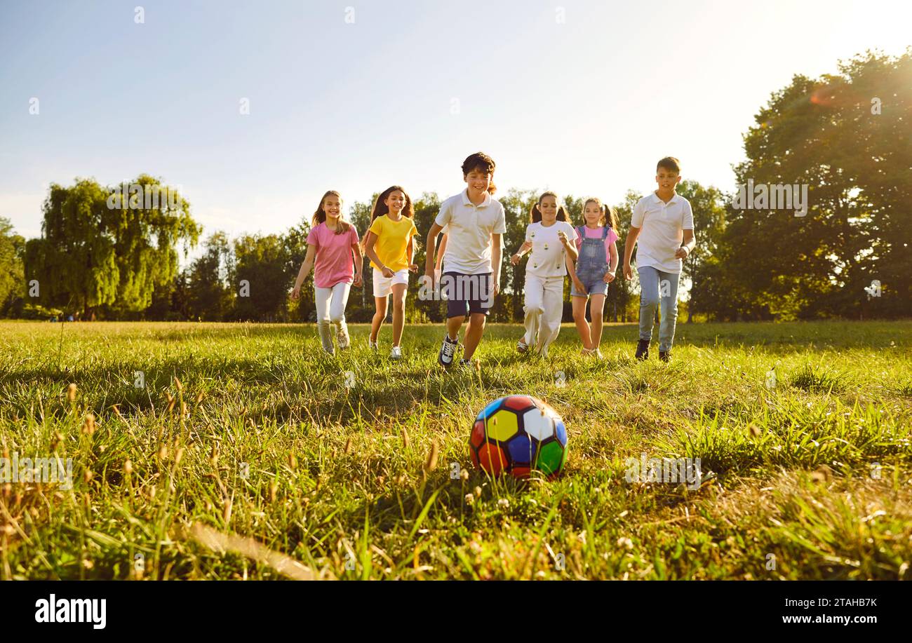 Fröhliche Kinder Jungen und Mädchen Rennen in den Sommerferien auf Ball zu spielen zusammen. Stockfoto