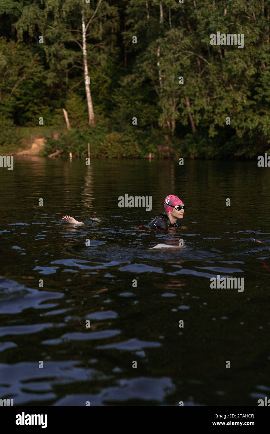 Professioneller Schwimmer in einem Neoprenanzug schwimmt im offenen Wasser auf einem See. Stockfoto
