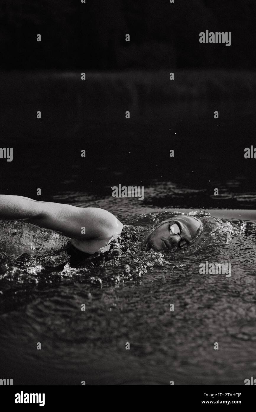 Professioneller Schwimmer in einem Neoprenanzug schwimmt im offenen Wasser auf einem See. Stockfoto