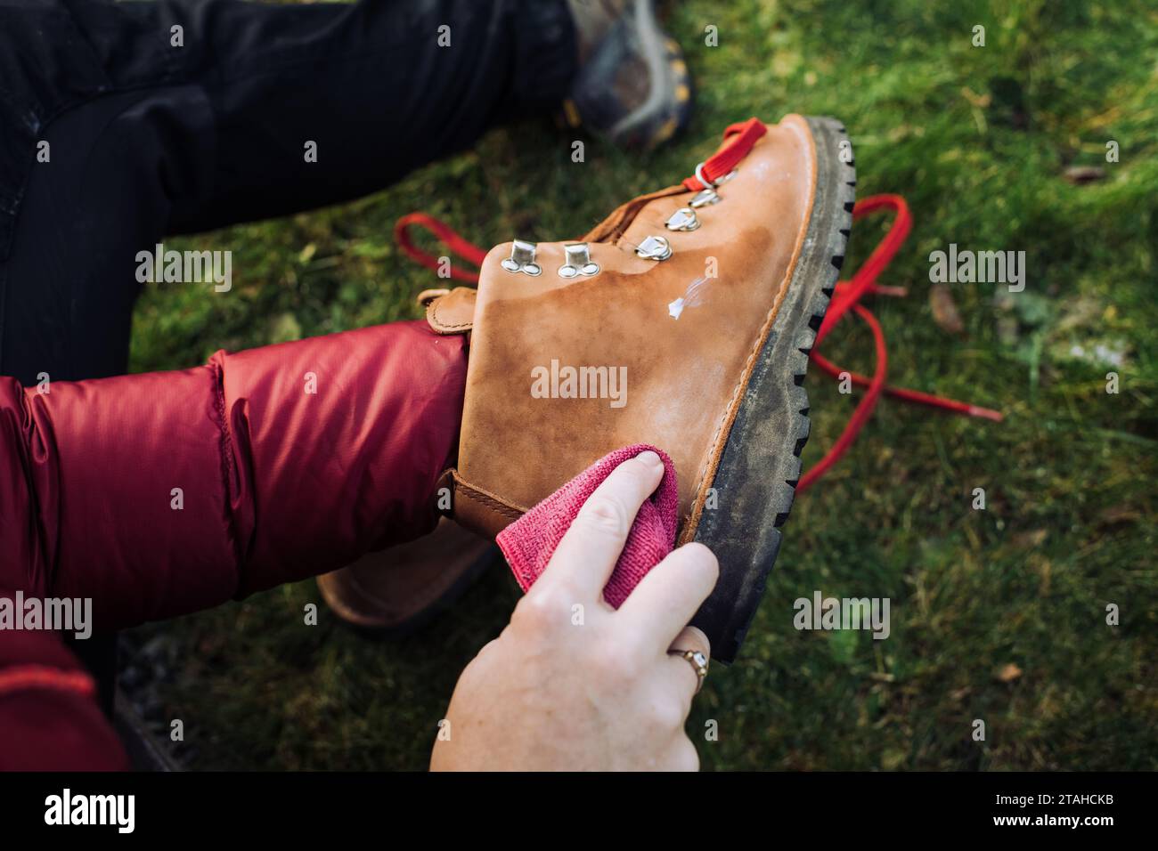 Frau, die ihre Wanderschuhe putzt, während sie draußen zu Hause ist Stockfoto