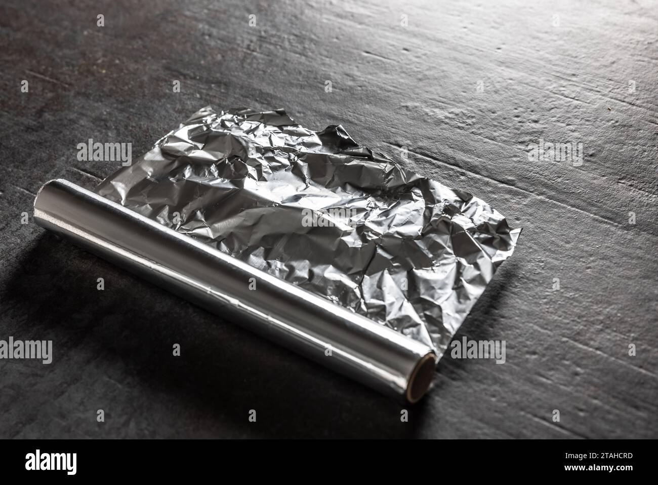 Aluminiumfolie auf dunklem Betonhintergrund. Stockfoto