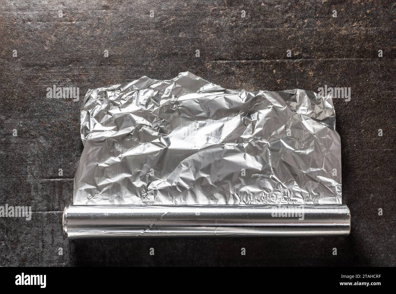 Aluminiumfolie auf dunklem Betonhintergrund. Stockfoto