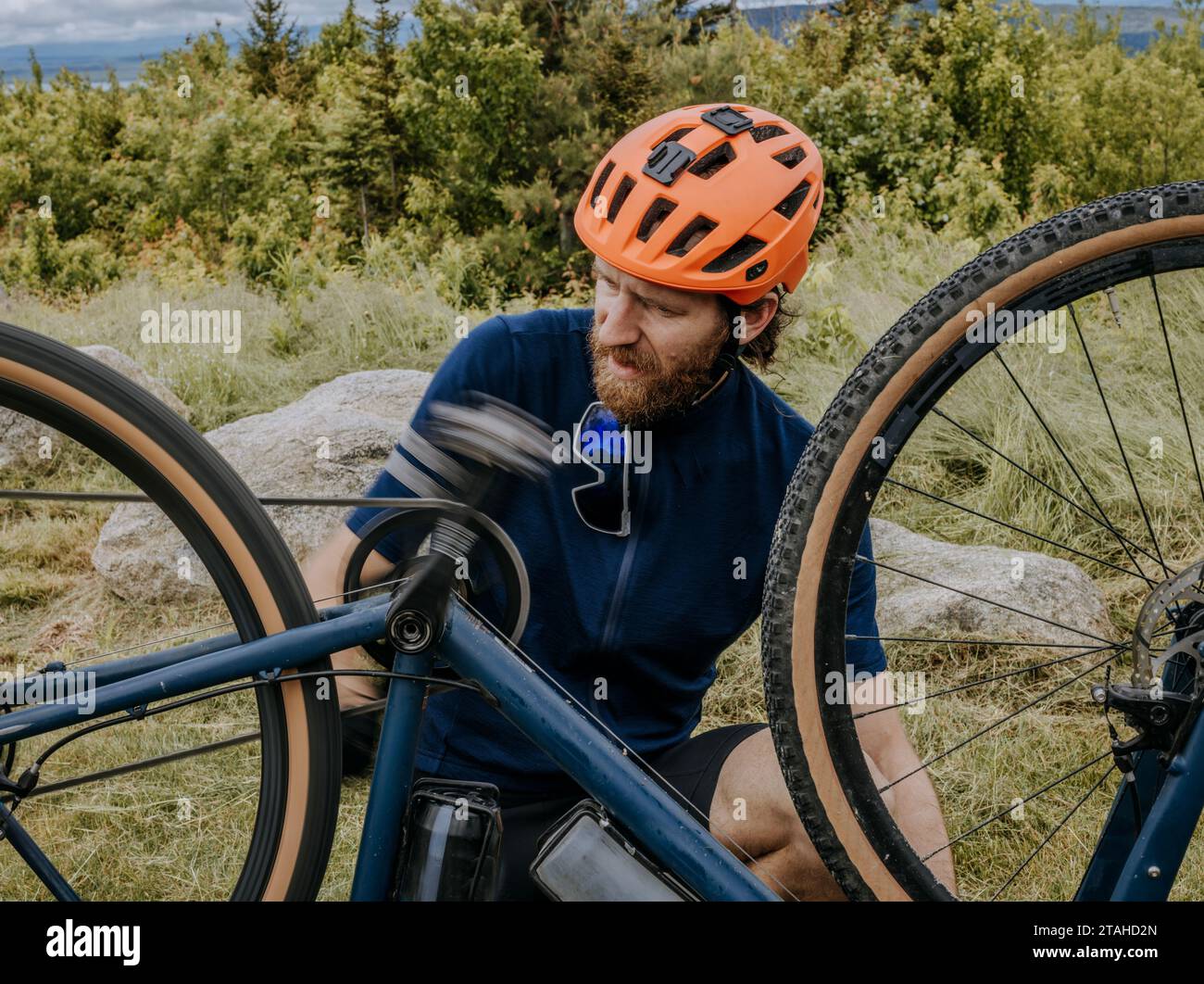 Ein Mann im Radsport hemet arbeitet an der Wartung seines Fahrrads in Maine Woods Stockfoto