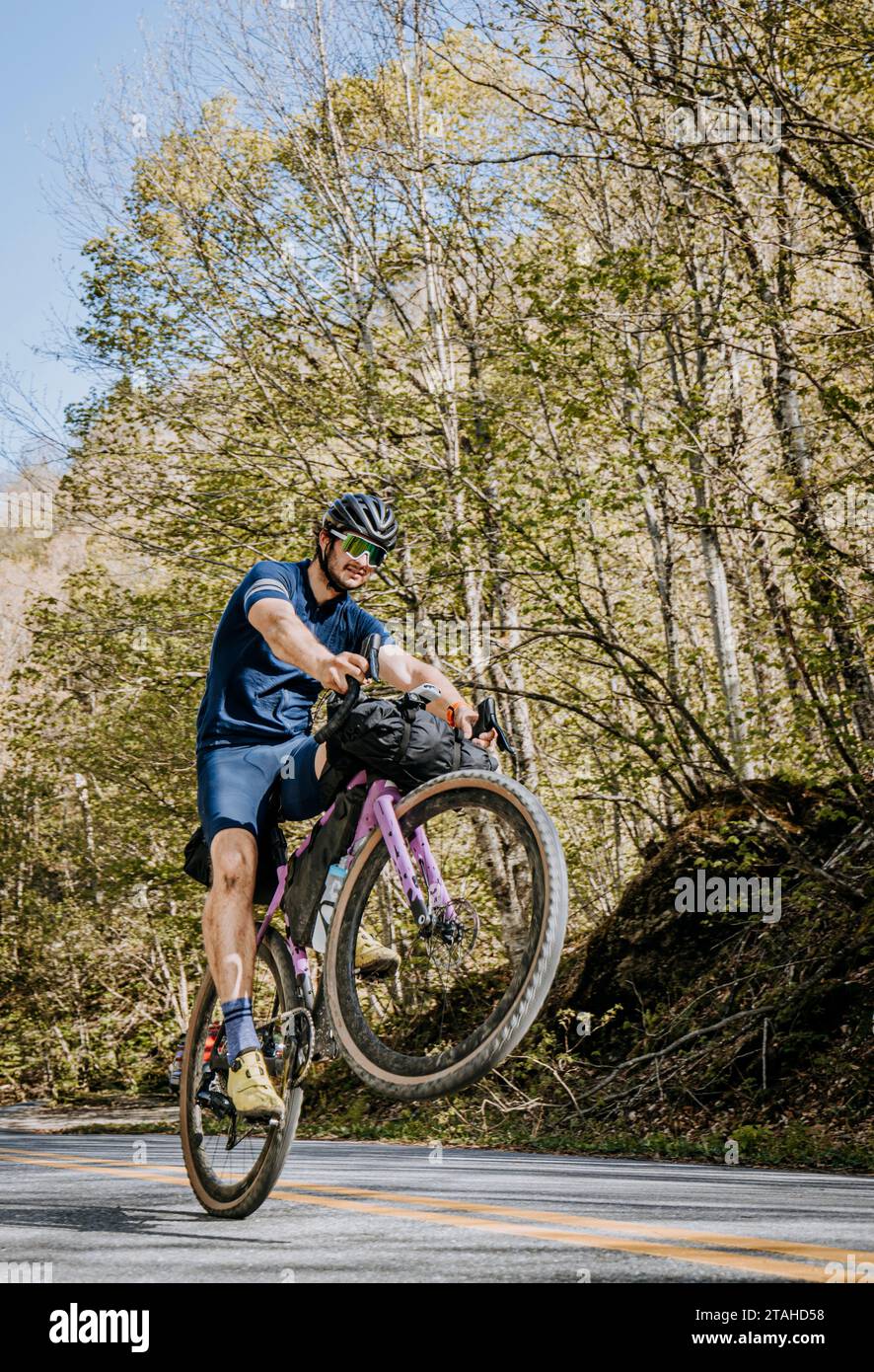 Radfahrer auf einem lila Fahrrad knallt ein Wheelie, während sie durch Vermont fahren Stockfoto