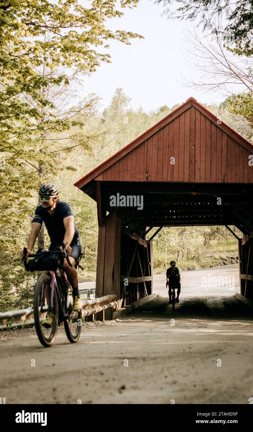 Zwei Radfahrer fahren durch eine überdachte Brücke im ländlichen Vermont Stockfoto