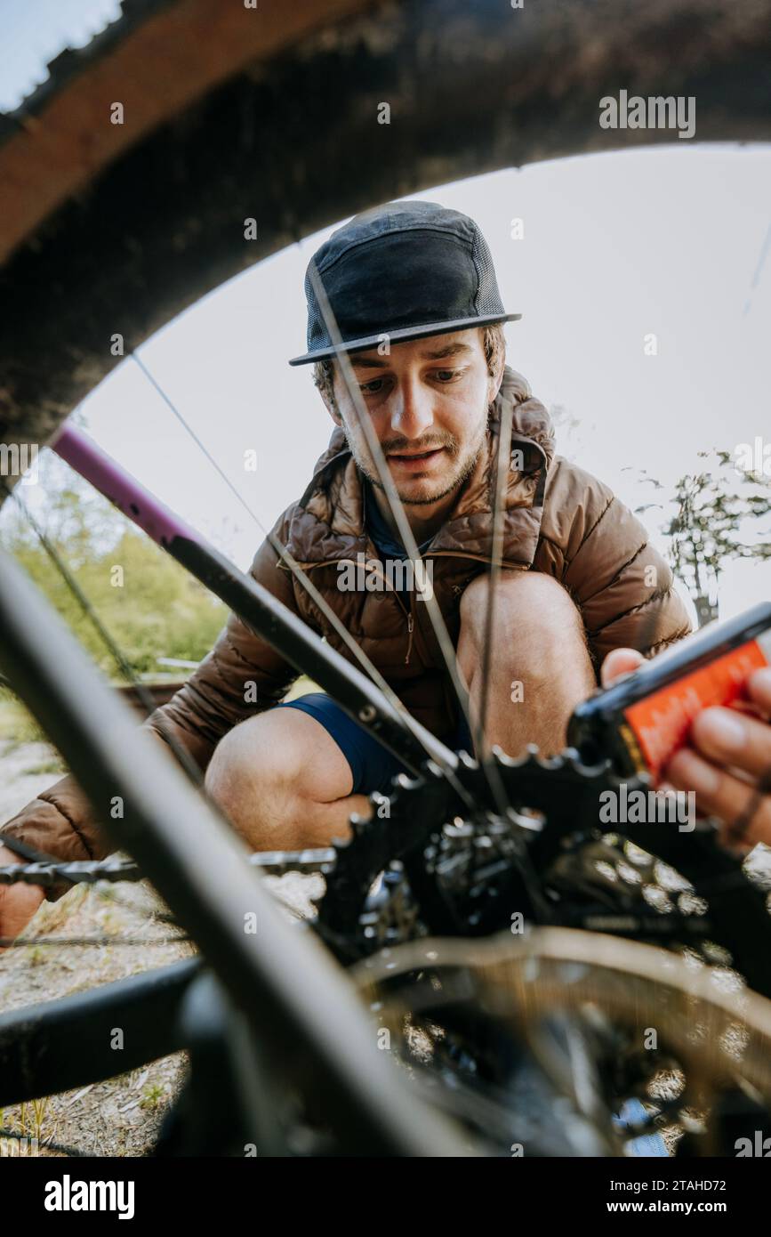 Ein junger Mann in Schwarz hat seiner Fahrradkette Kettenöl hinzugefügt Stockfoto