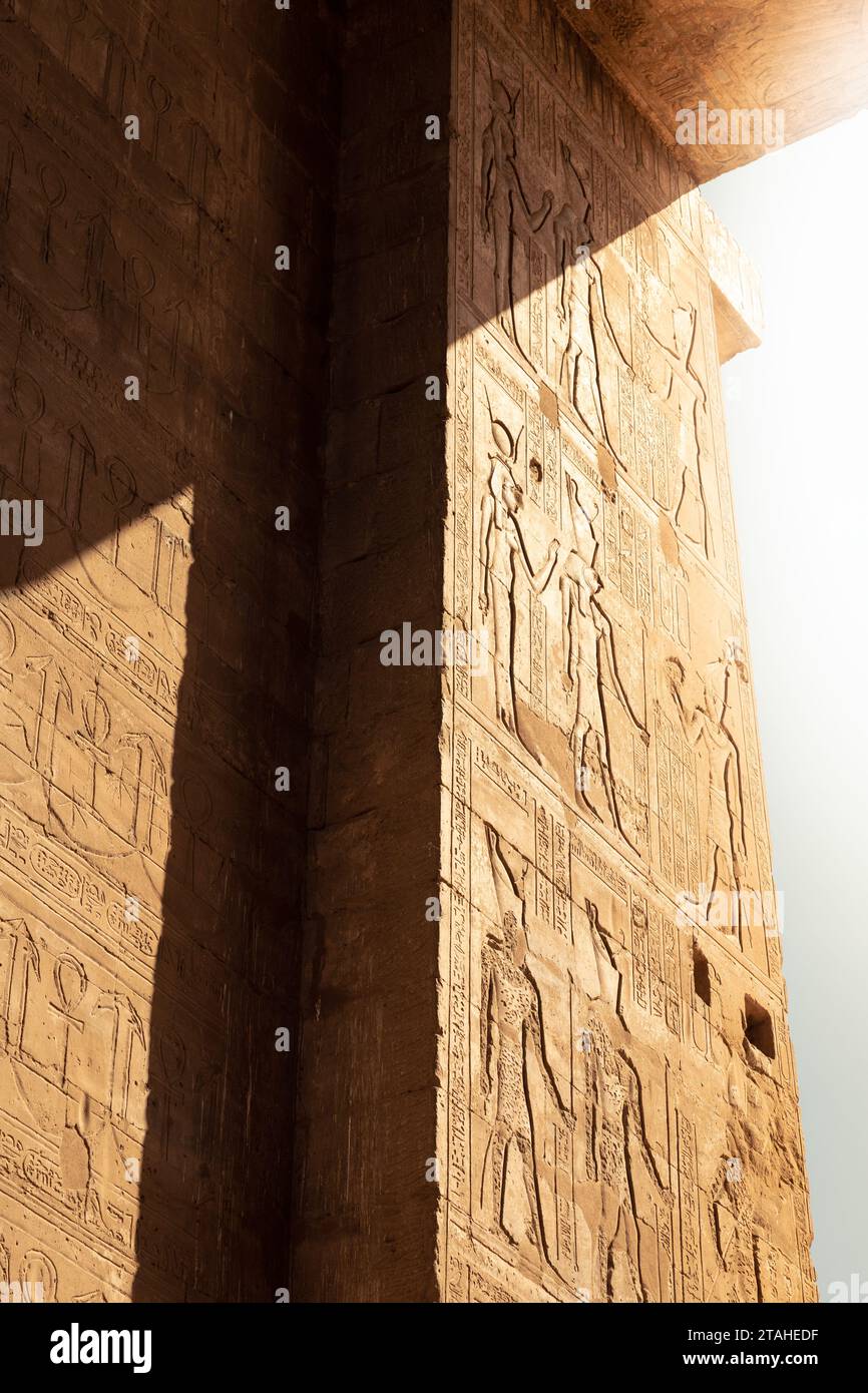 Goldener Sonnenstrahl, der die mit ägyptischen Hieroglyphen bedeckten Wände erreicht Stockfoto