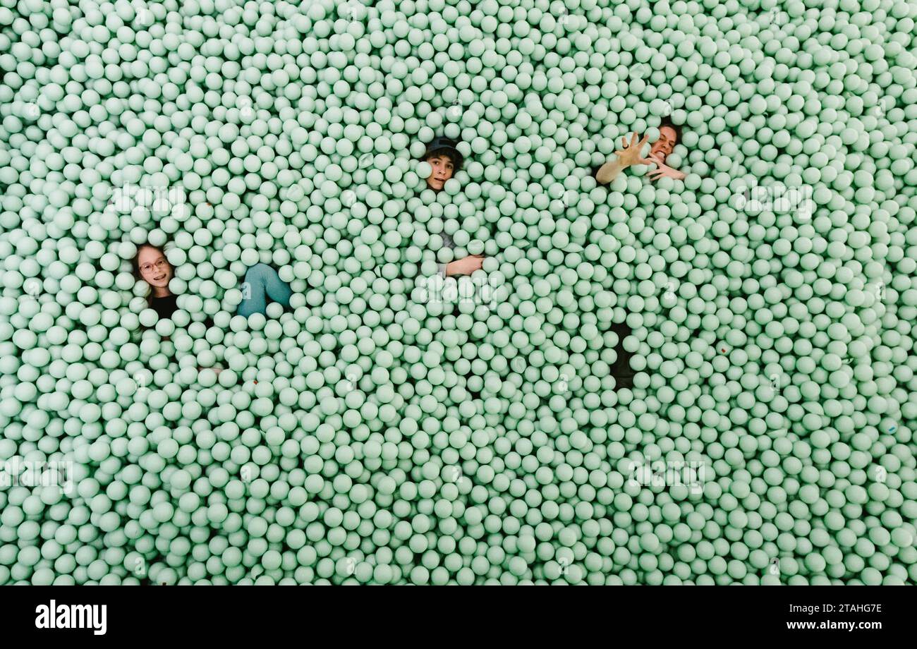 Drei Teenager-Kinder in einem riesigen grünen Ball, die albern und lustig sind Stockfoto